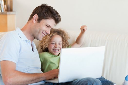 Cheerful boy and his father using a laptop in their living room