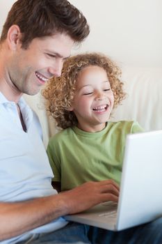 Portrait of a cute boy and his father using a laptop in their living room