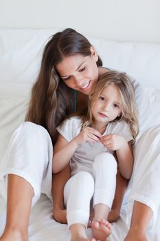 Portrait of a mother and her daughter posing on a bed looking away from the camera