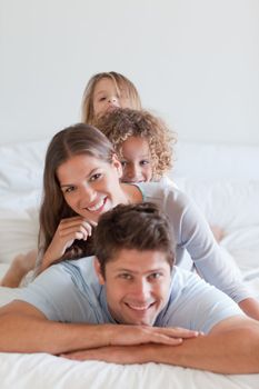 Portrait of a family lying on each other in a bedroom