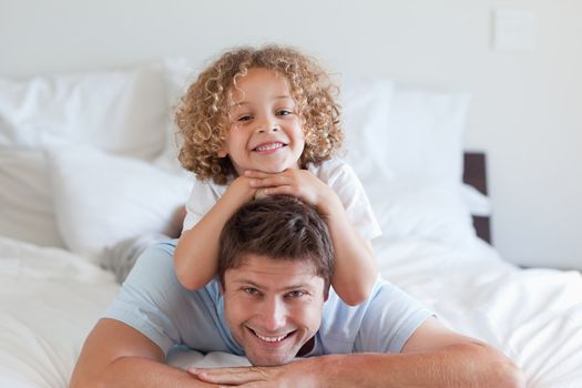 Child lying on fathers back in bed
