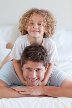 Smiling father and child lying on bed together