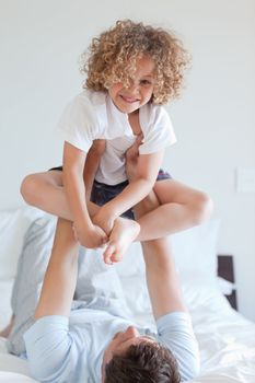 Father lifting smiling child on bed