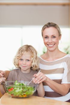 Smiling mother and son stirring salad together