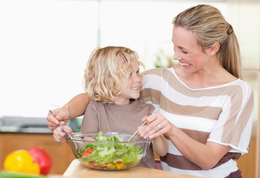 Happy mother and son preparing salad together
