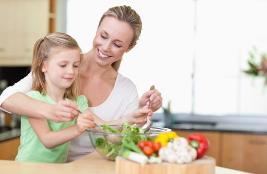 Mother and daughter stirring salad together