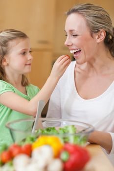 Little girl feeding her mother with salad