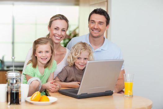 Smiling family using the internet together in the kitchen