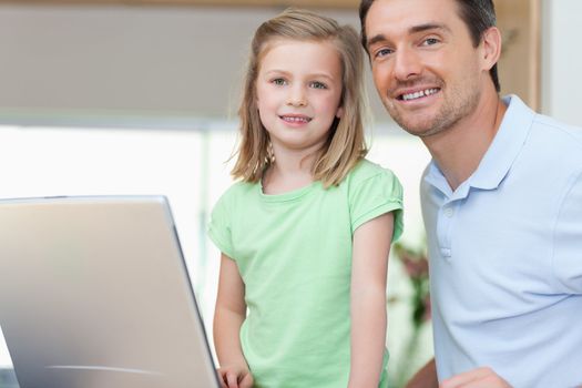 Smiling father and daughter together with laptop