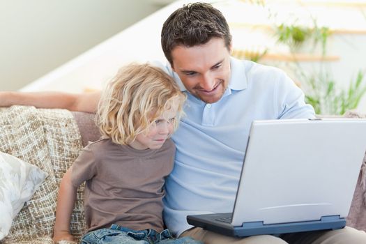 Father and son together with laptop on the sofa