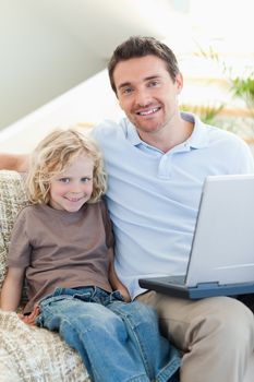 Father and son together on sofa with laptop