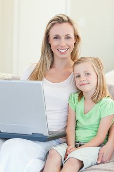 Mother and daughter together with laptop on sofa