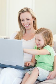 Mother and daughter together with laptop on couch