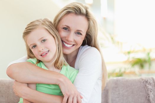 Mother hugging her daughter on the sofa