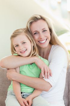 Mother hugging her daughter on the couch