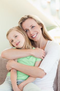 Mother embracing daughter on the sofa