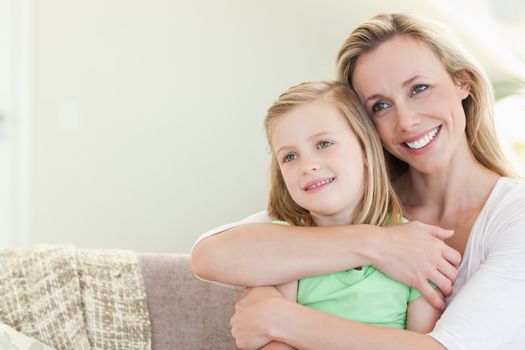 Mother embracing daughter on the couch