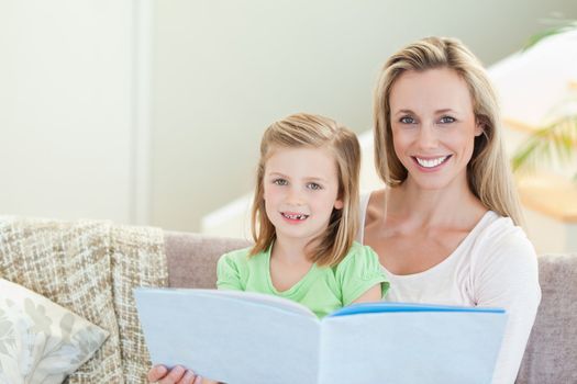 Mother and daughter reading a magazine together on the sofa