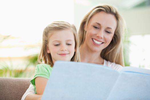 Mother and daughter reading a magazine together on the couch