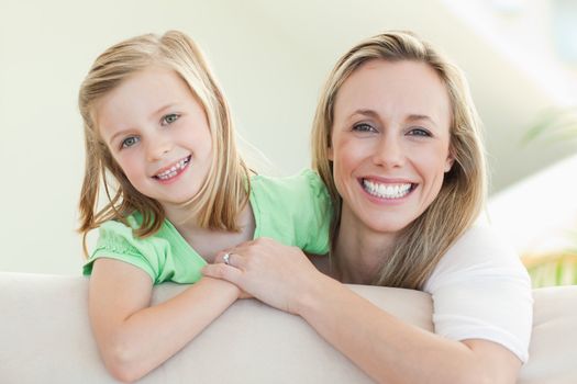 Smiling mother and daughter together on the sofa