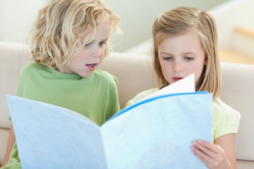 Siblings on the sofa reading magazine together