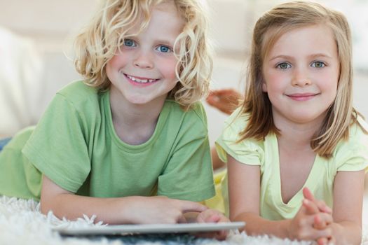 Siblings using tablet together on the floor