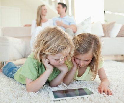 Children on the floor together with tablet and parents behind them