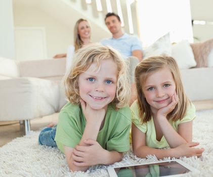 Children on the carpet together with tablet and parents behind them