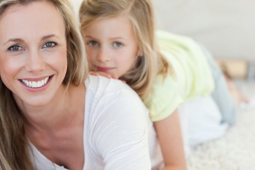 Mother and daughter lying together on carpet