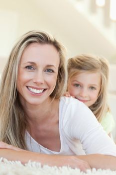 Smiling mother and daughter together on the carpet