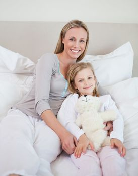 Mother and daughter sitting together on bed