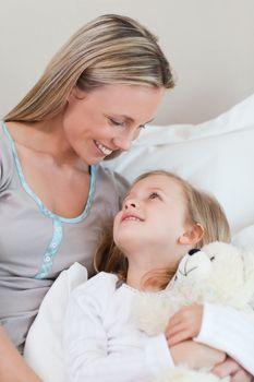 Smiling mother hugging her daughter on the bed