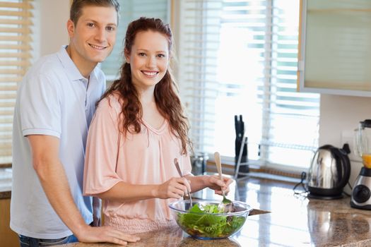 Young couple with salad in the kitchen
