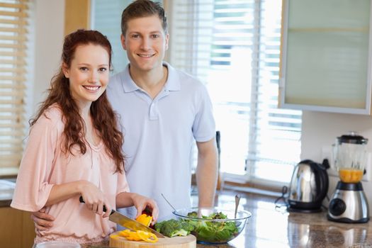 Smiling couple in the kitchen preparing salad