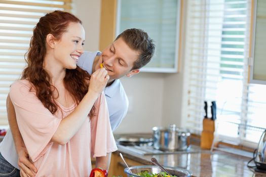 Young woman giving her boyfriend some bell pepper