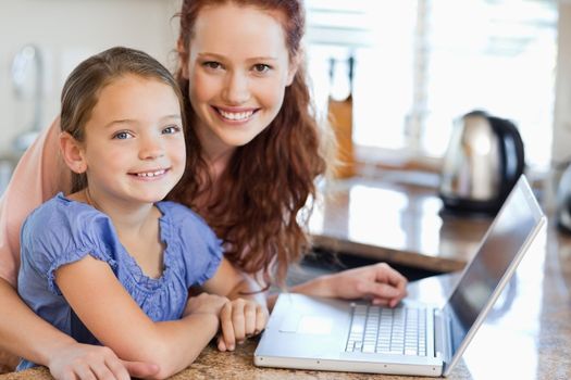 Mother and daughter together with notebook in the kitchen