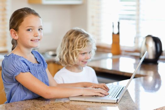 Siblings together with laptop behind the kitchen counter
