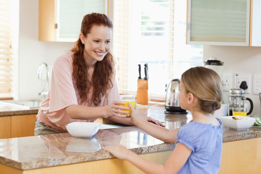 Mother giving her daughter a glass of orange juice