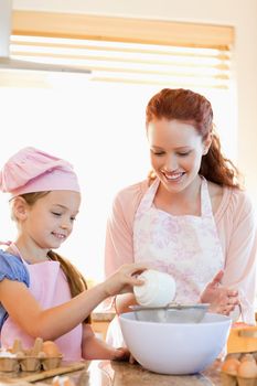 Cheerful mother and daughter preparing dough together
