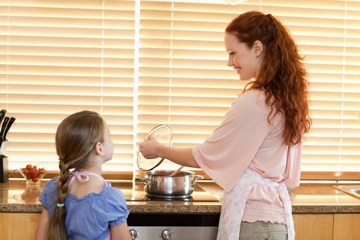 Smiling mother showing her daughter what shes cooking