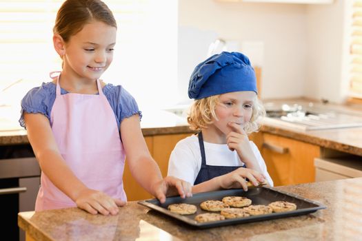 Siblings stealing cookies off the kitchen counter
