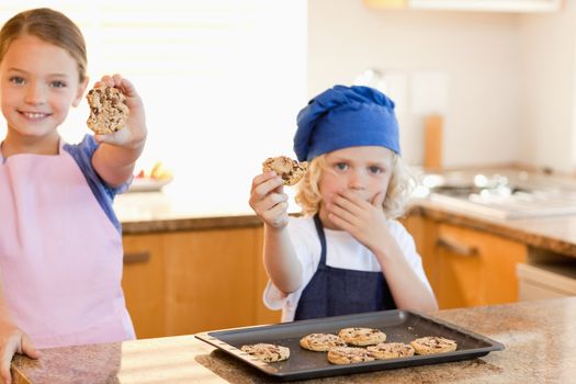 Siblings showing their cookies in the kitchen