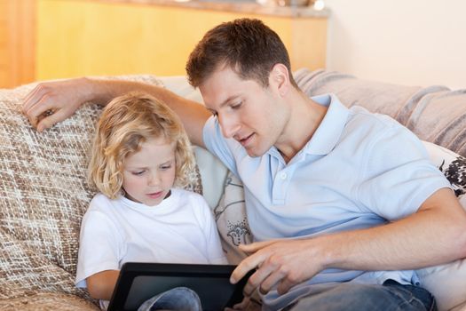 Father and son using tablet on the sofa together