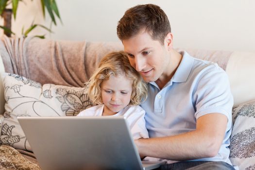 Father and son surfing the internet on the sofa