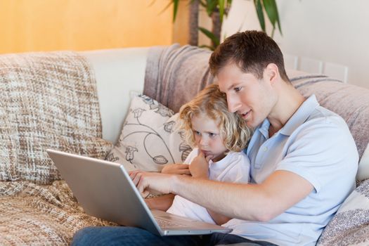 Father explaining his son the internet on the sofa