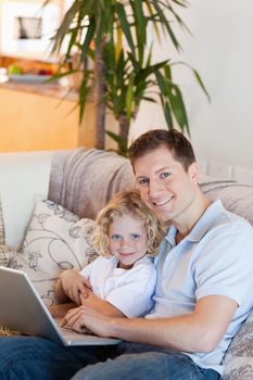Father and son together with laptop on the sofa