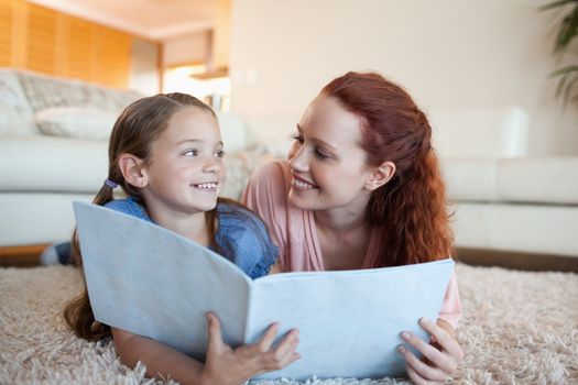 Mother and daughter together with periodical on the floor