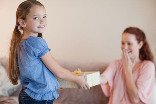 Girl giving her surprised mother a present