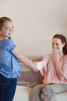 Little girl giving her surprised mother a present