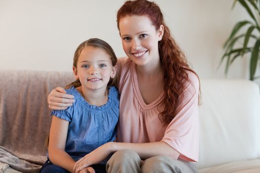 Happy smiling mother and daughter on the sofa